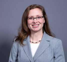Dr. Bozlak smiles at the camera, wearing a white shirt and a grey blazer.