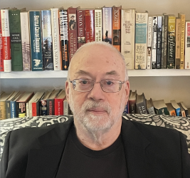 Charles Lanier poses in front of a bookcase. 