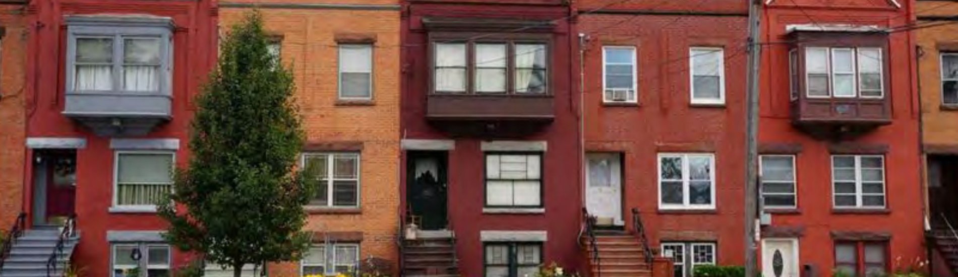 An image of a row with 5 townhomes and two cars parked in front of the townhomes.