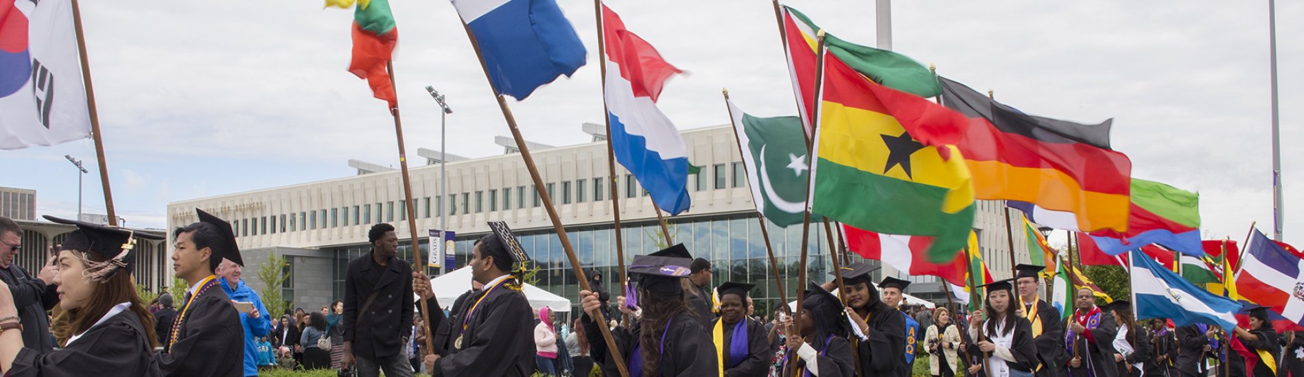 Students holding flags from their countries at commencement.
