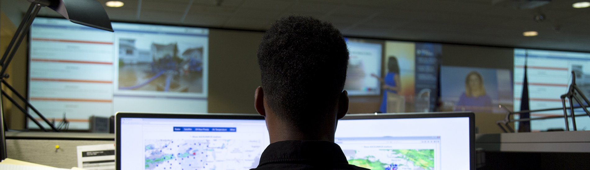 Student working in front of two monitors in an emergency operations center.