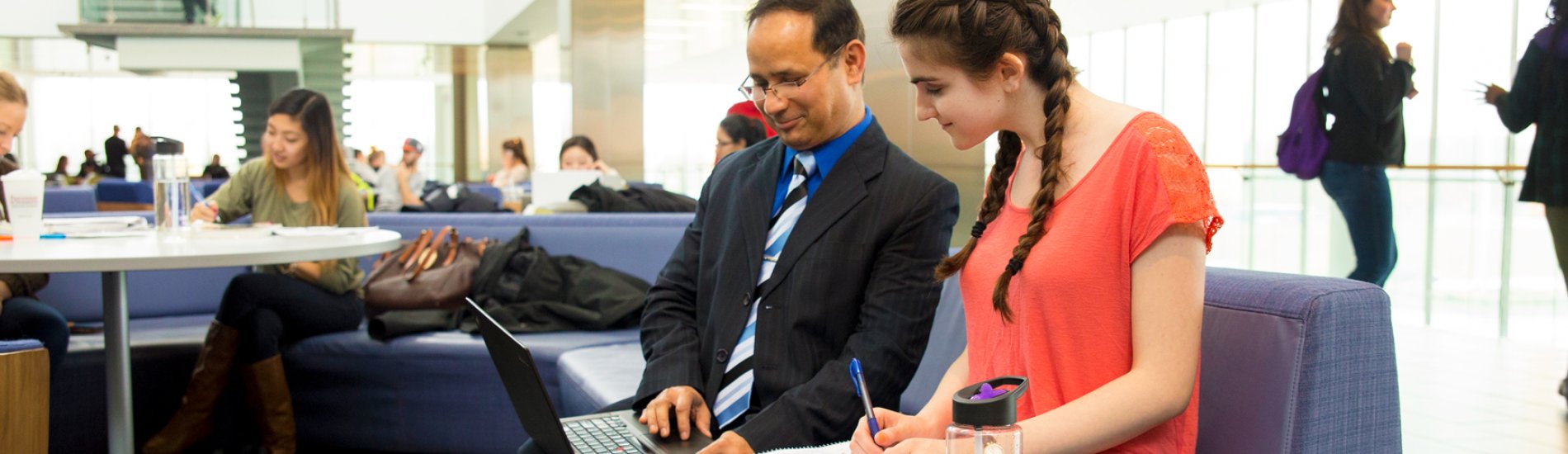 UAlbany professor Pradeep Atrey works with a student on a laptop computer.