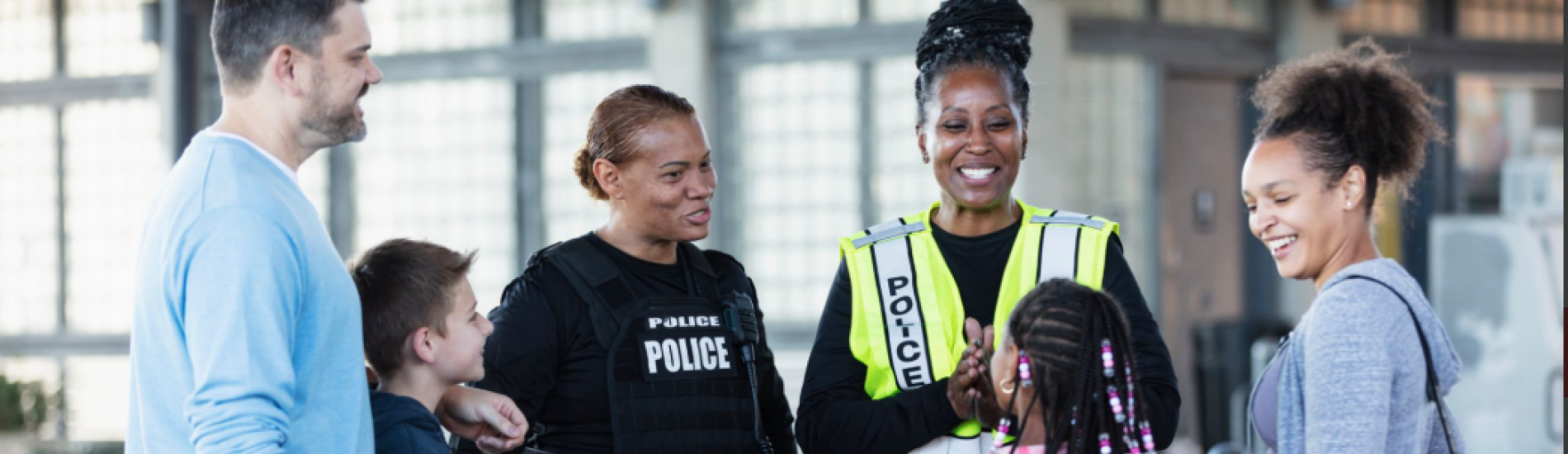 Two smiling police officers talk with parents and children.