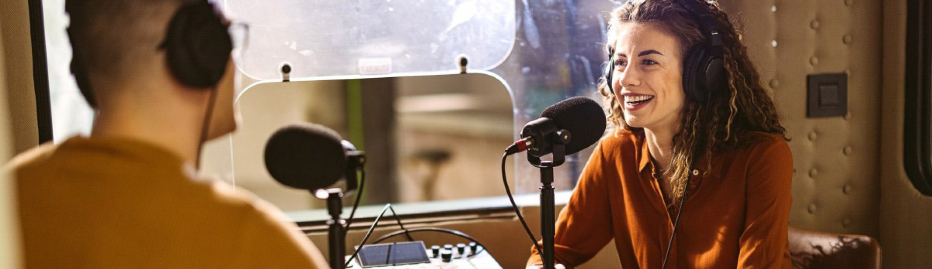 A podcast host interviews a guest in a recording studio.