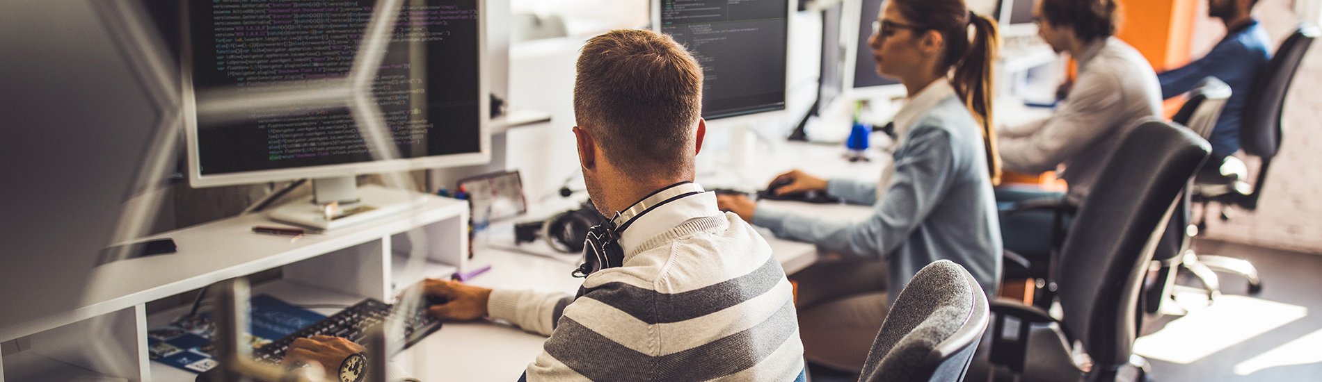 Group of programmers developing new software on desktop computers in an office.