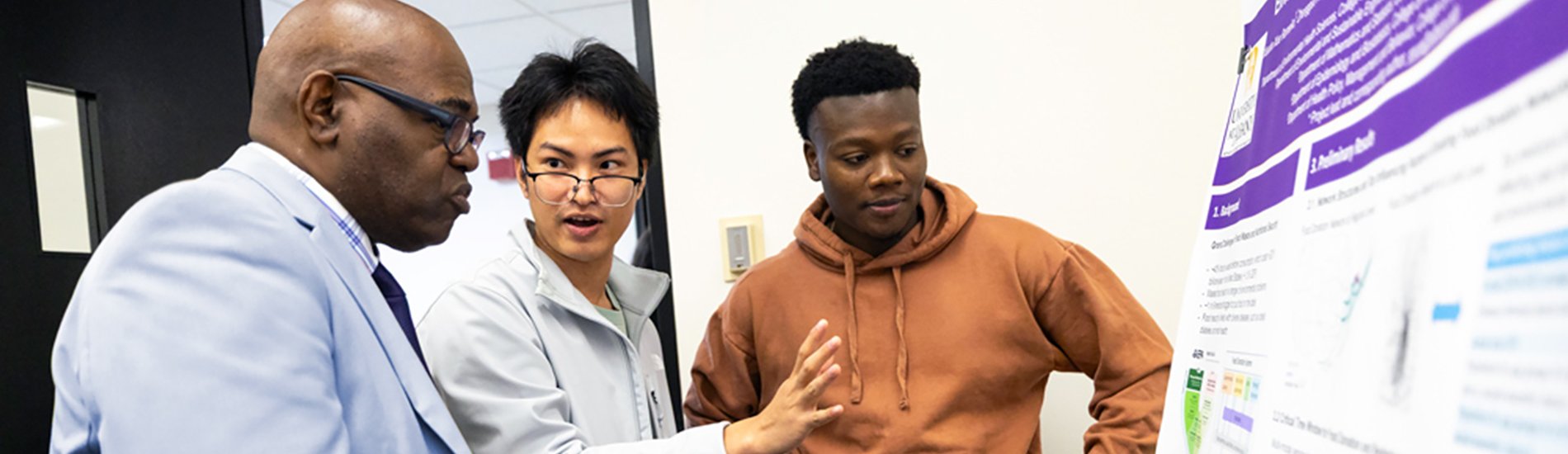 Three people having a discussion at a research poster session.
