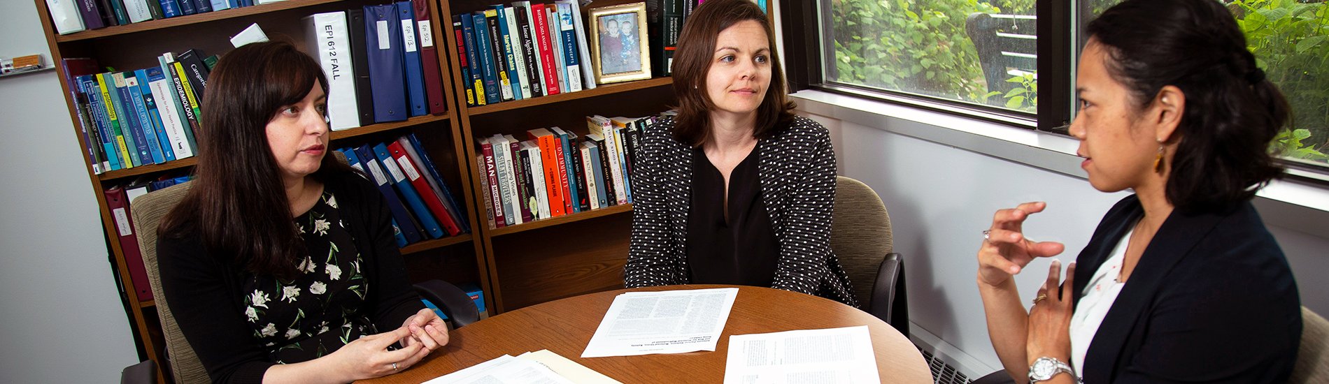 Three people having a discussion while seated at a small conference table.