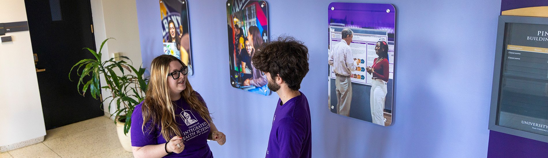 Two students having a conversation in the UAlbany College of Integrated Health Sciences hallway.