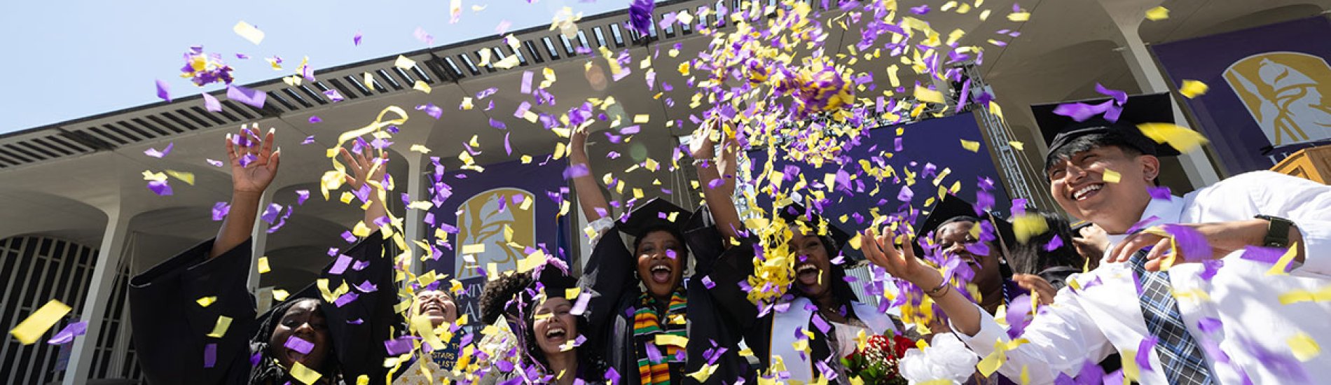 Students posing together as confetti flies at commencement