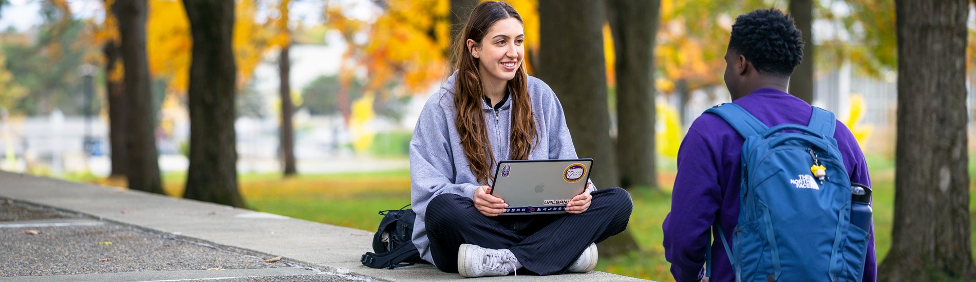 Two students talking outside during Fall on the UAlbany campus.