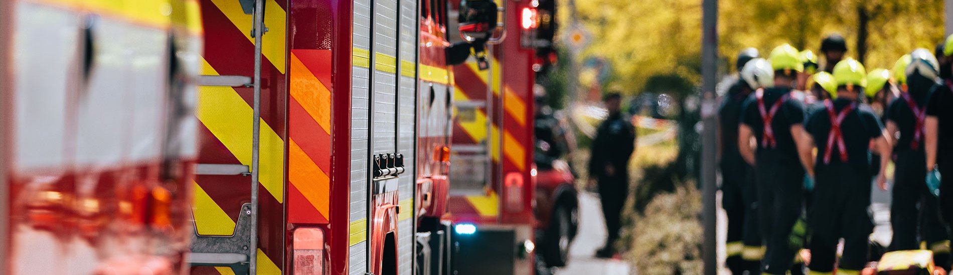 A group of first responders gather next to a line of fire engines to plan an emergency response.