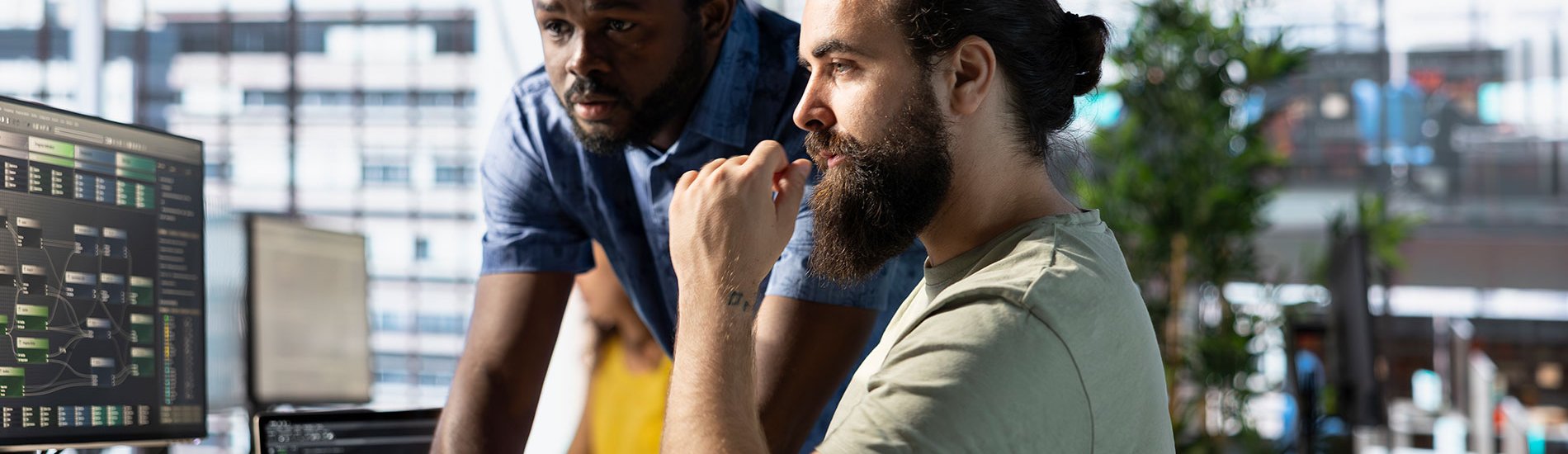 Two ethical hackers review code on a monitor.