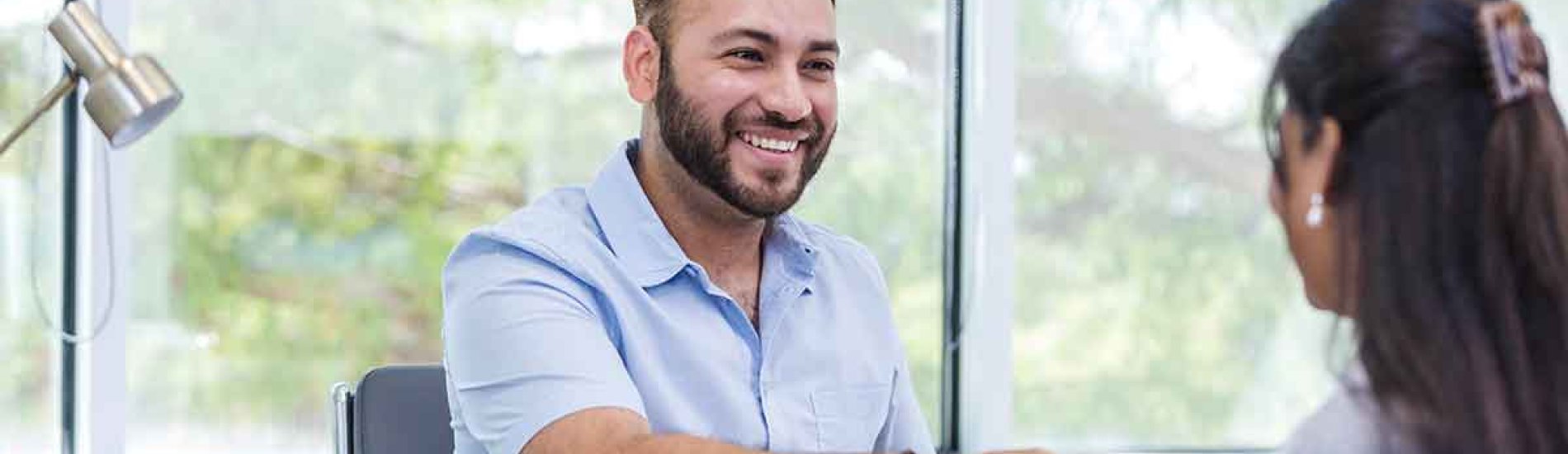 A career counselor seated at a desk shakes hands with a client.
