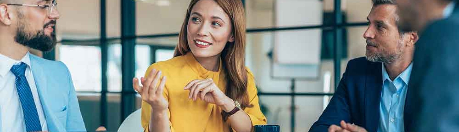 A group of colleagues talking as they sit at a conference table.