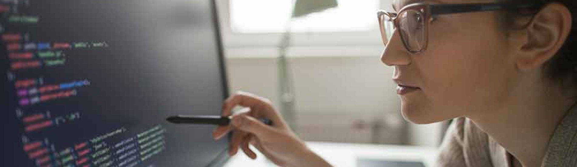 A cybersecurity professional analyzes code on a monitor.