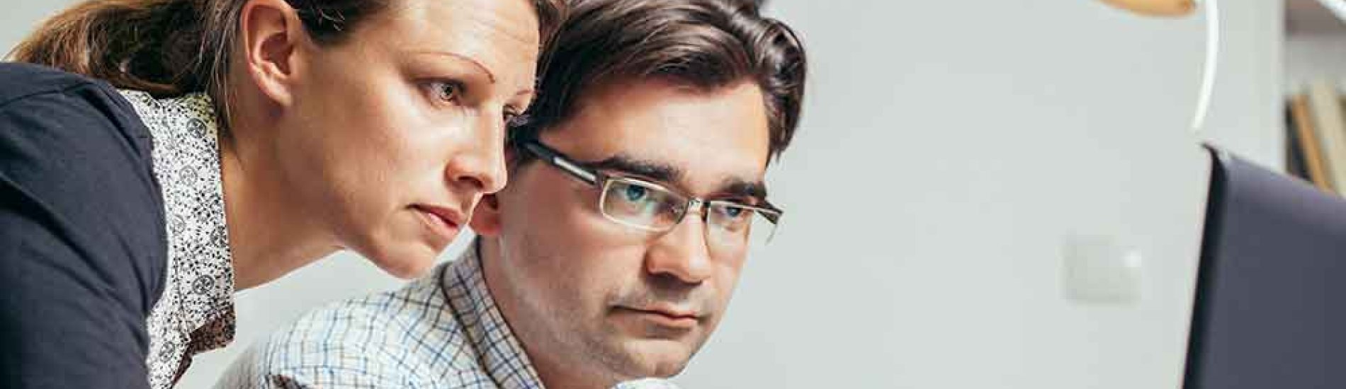 Two cybersecurity analysts in an office review an issue.