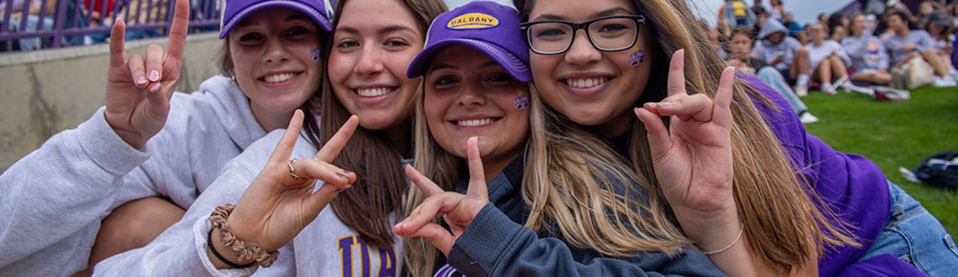 Four students making a Damien hand sign.