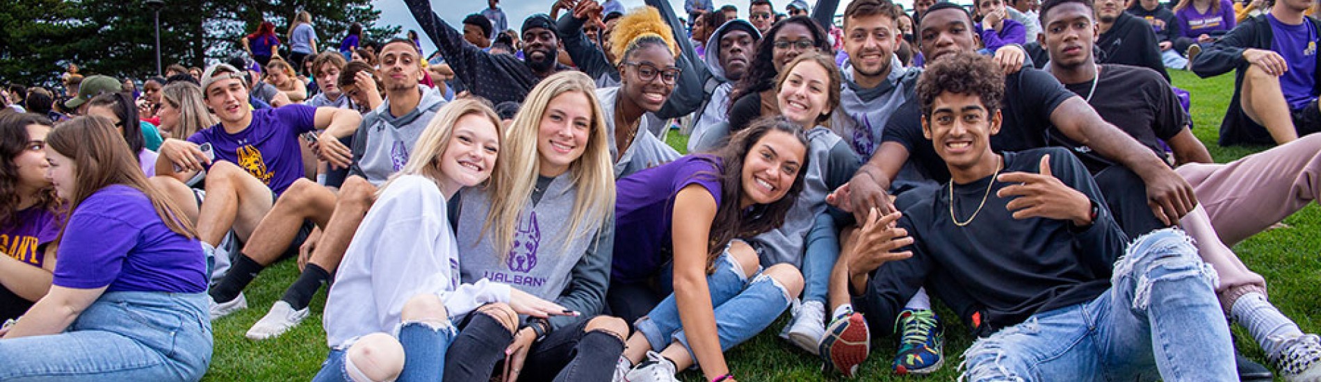 Students sitting in the grass together at Homecoming.