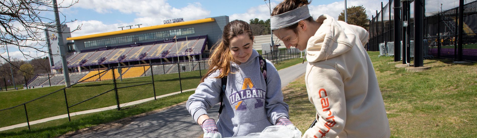 Two students collect litter on UAlbany's Uptown Campus for Earth Day.