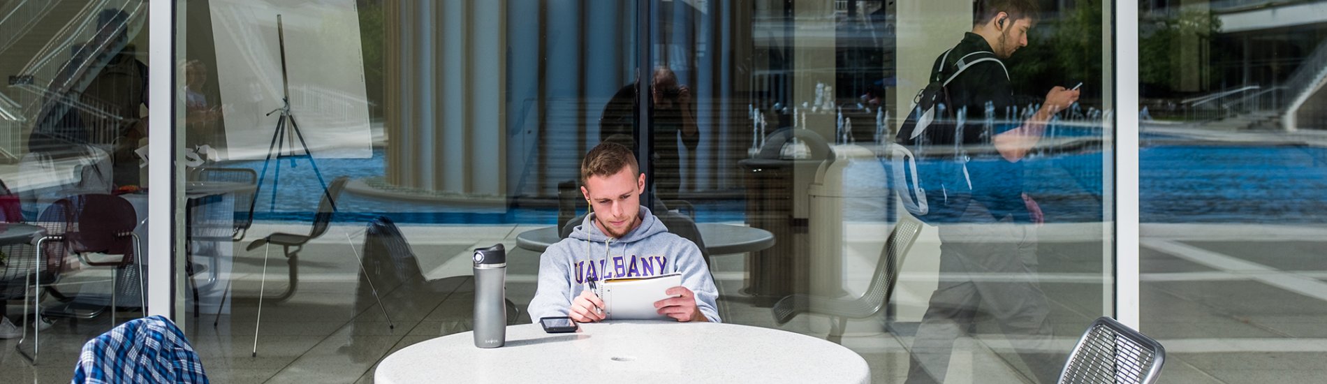 A student studying at a table by the UAlbany main fountain.
