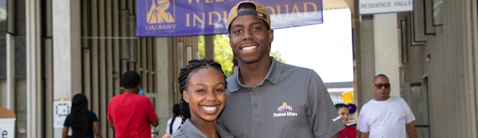 Two Resident Assistants pose for a photo outside Indigenous Quad on move-in-day