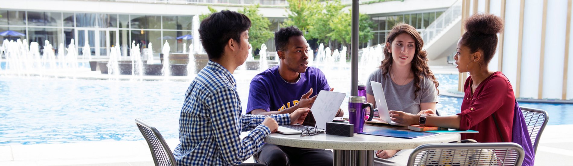 Group  of students studying at a table next to the UAlbany main fountain.