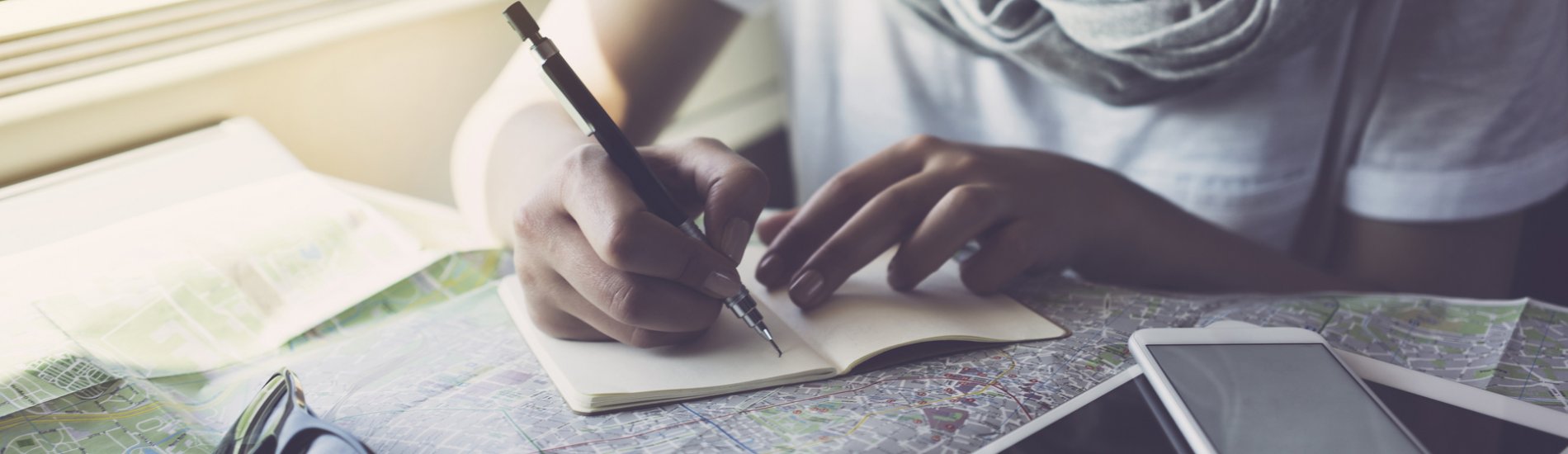 Young woman on a train taking notes over an open map