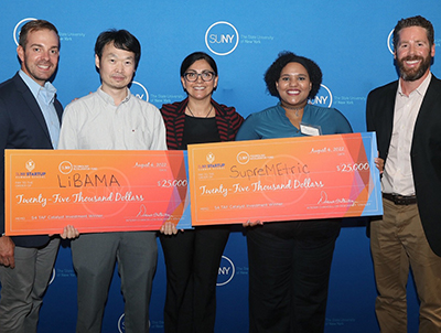 People stand with oversized checks in front of a SUNY backdrop