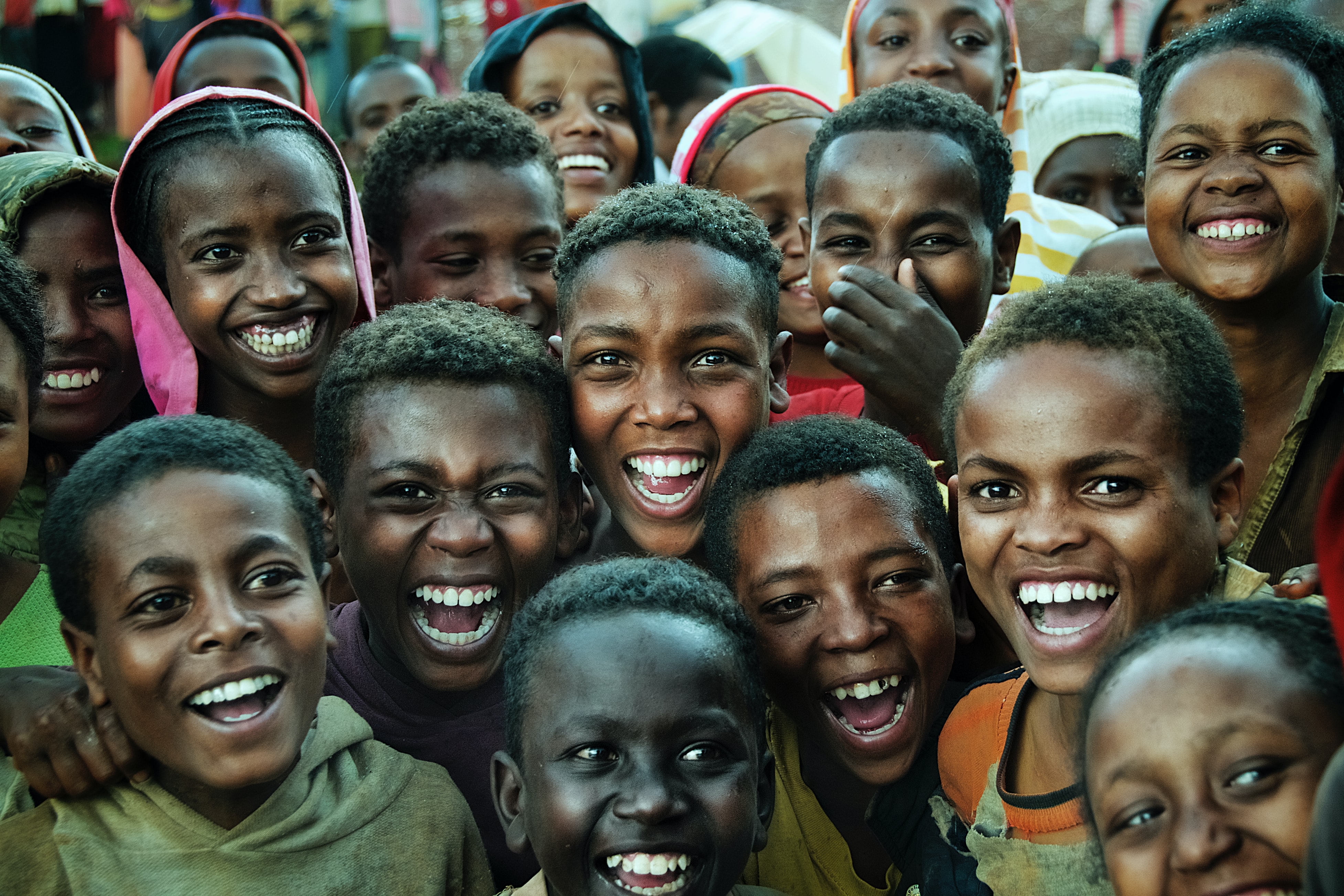 A group of children gathered together joyfully smile at the camera.