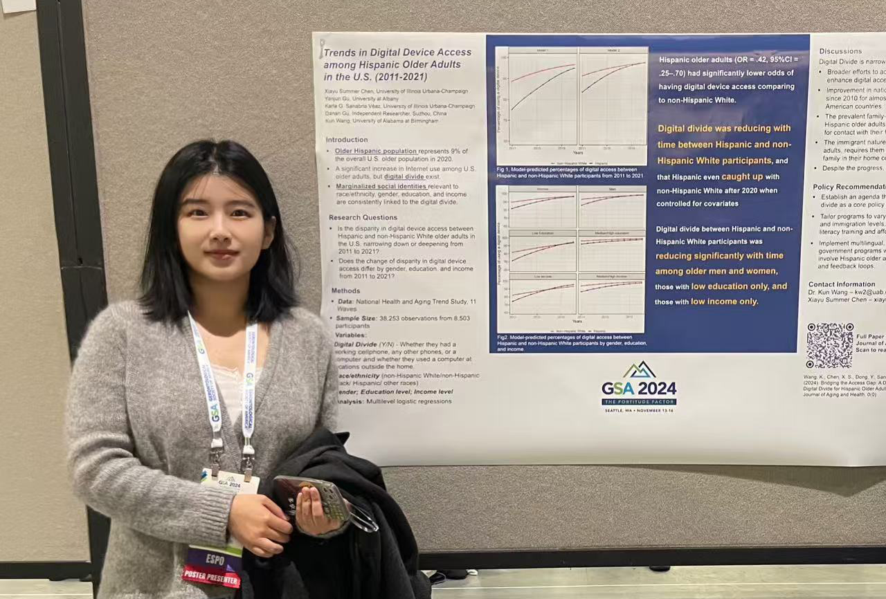 A young woman with short black hair and a grey sweater stands next to a poster pinned to a gray presentation board.