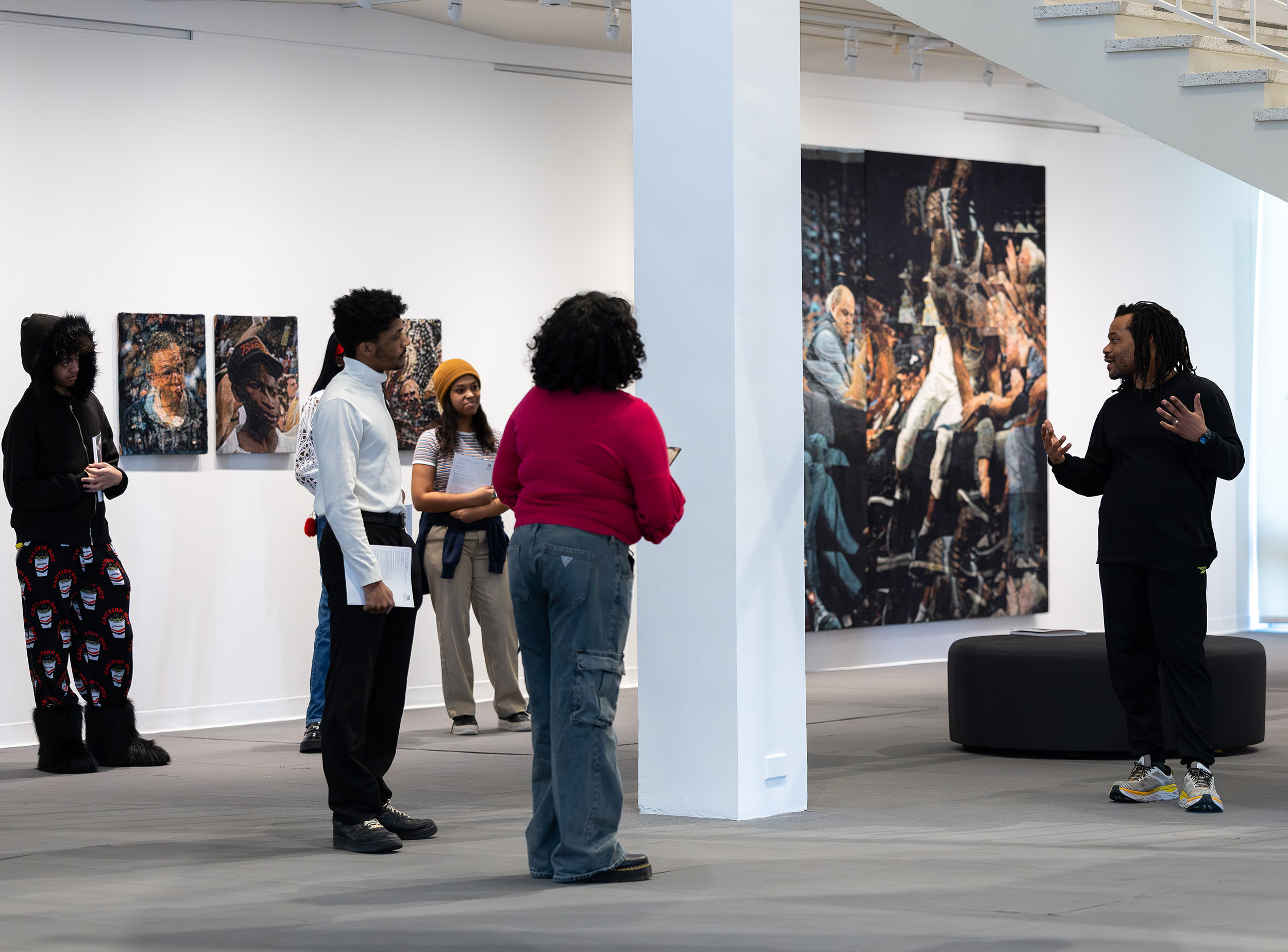 Students listen to artist Noel Anderson on the far right as he discusses his work on display inside the University Art Museum at UAlbany.