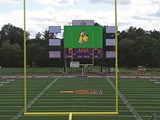 A state-of-the-art video screen is mounted atop the scoreboard. The two dotted screens on either side are also video screens; the four white rectangles are advertising boards.