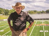 Coach Bob Ford, who has announced he will retire after the end of the current season, poses in front of the field named for him.