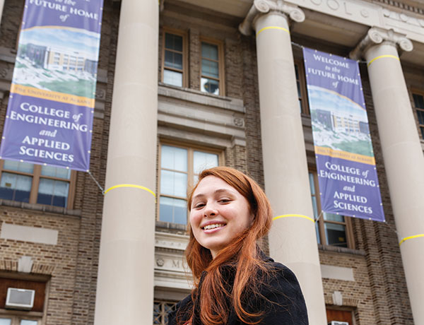 Student stands in front of new home of the College of Engineering and Applied Sciences