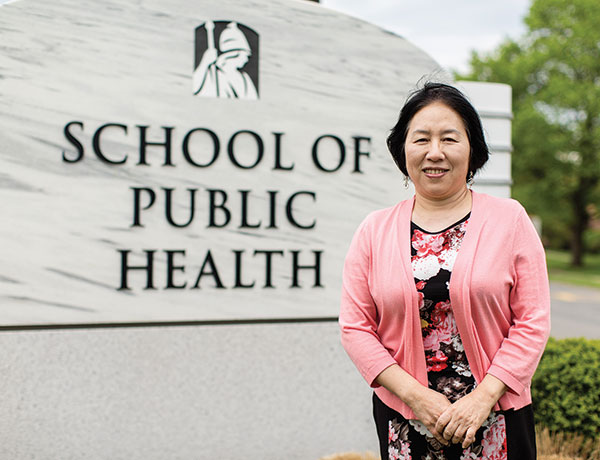 Professor Shao Lin stands in front of the School of Public Health building sign