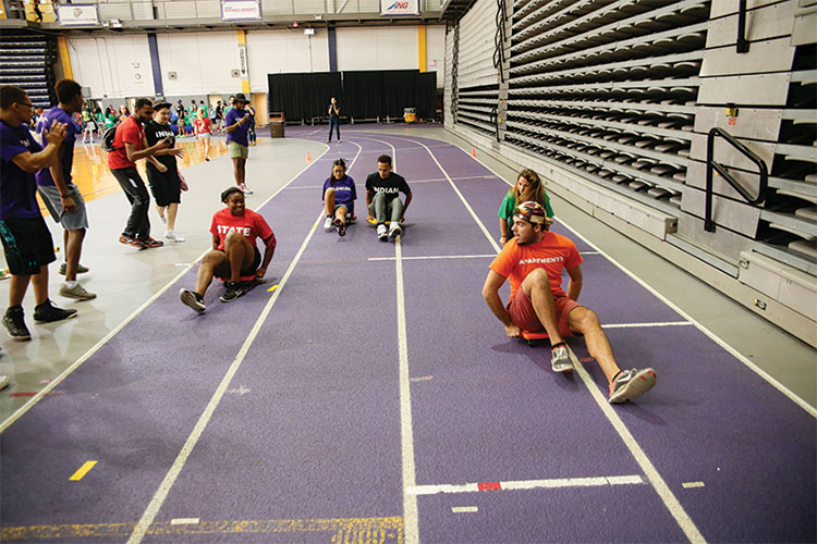 Students race on scooters on purple track.