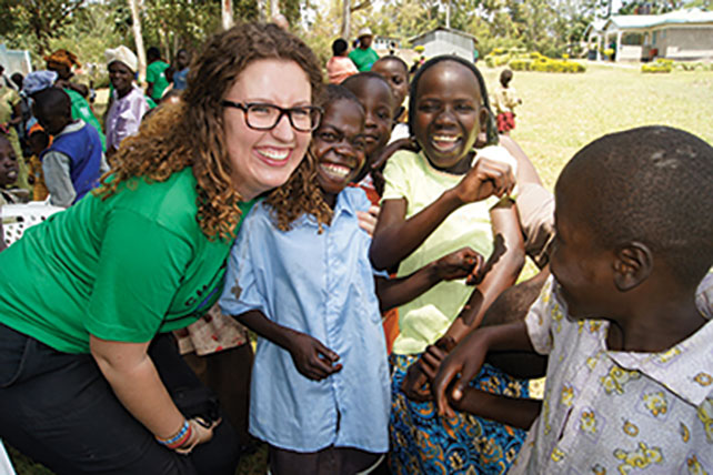 Student smiling with children in study abroad program.
