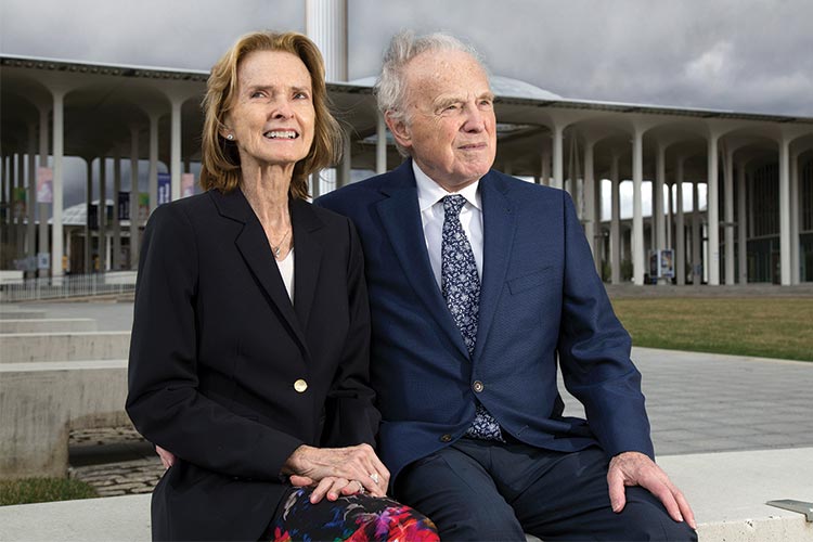 Daniel Wulff and Bonnie Taylor sit near the podium on UAlbany campus.