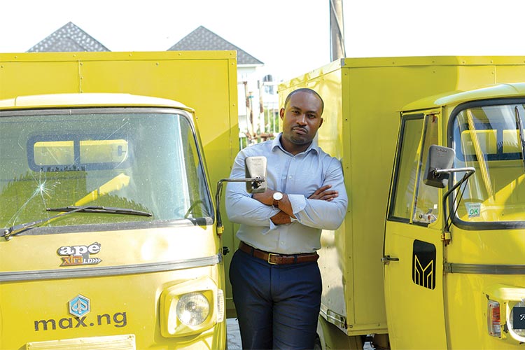 Nwokocha stands between two yellow max-ng vehicles.