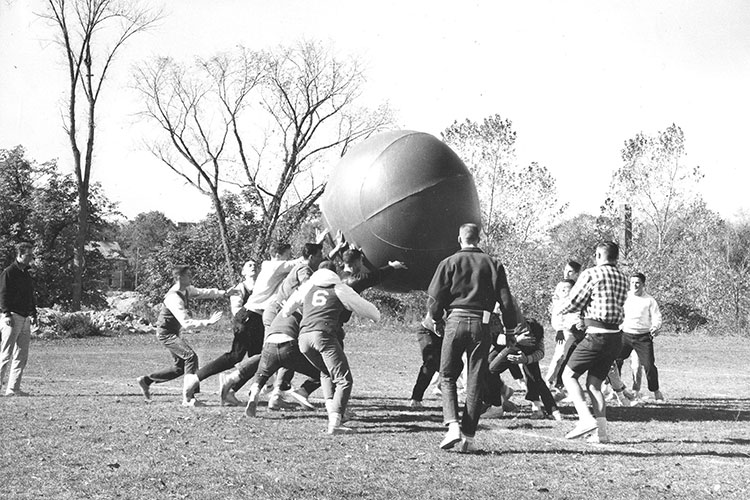Students run with giant basketball.