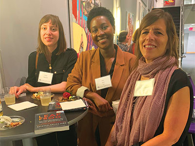 Alumni sit with author Nathalie Molina at table at SUNY Global Center.