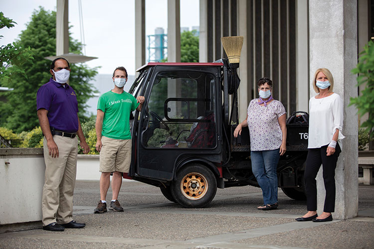 UAlbany staff wearing masks pose for a picture next to a small facilities car.