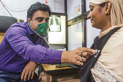 Doctor with green mask listens to a patient's lungs