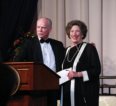 George Hearst stands at podium with Karen Hitchcock at Citizen Laureate Awards dinner ceremony