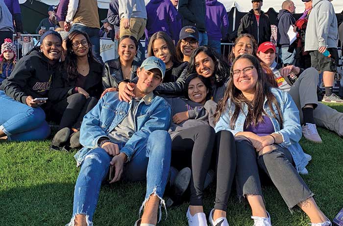 Recent grads on lawn cheer on the football team