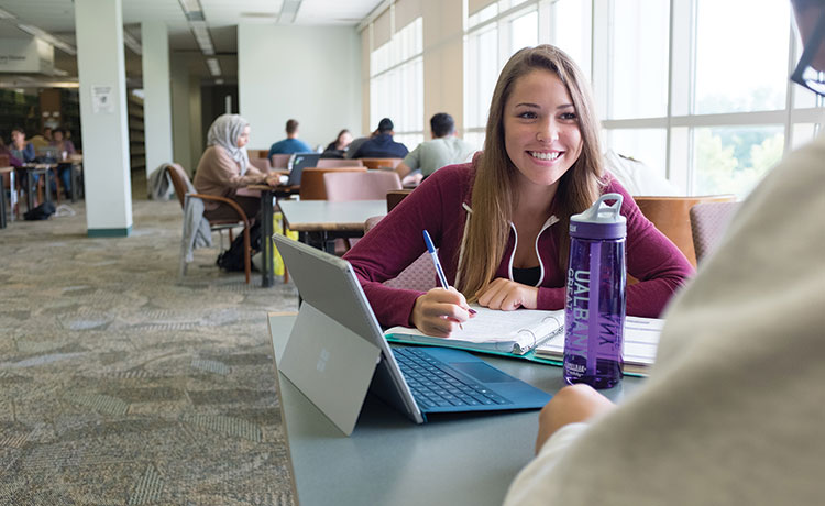 Student smiles as she studies in UAlbany science library in 2017