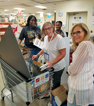 Three teachers and a shopping cart filled with supplies for the classroom