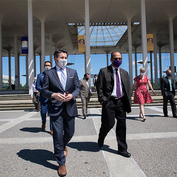 Malatras walks along entryway pathway with President Rodriguez and others.