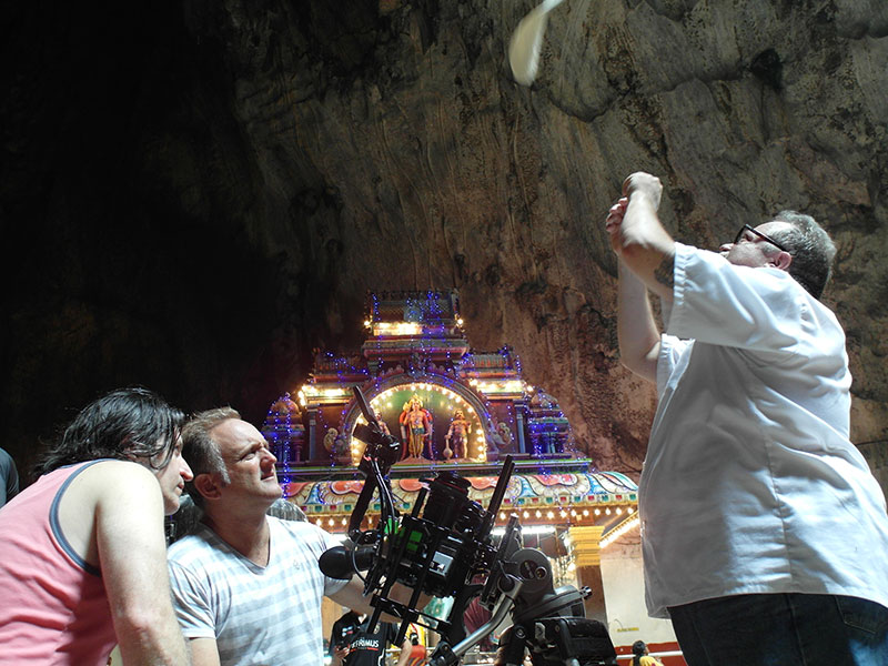 Man tosses pizza dough in the air in front of camera in Butu Caves of Malaysia