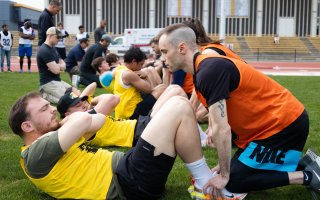 UAlbany students wear orange and yellow jerseys while completing sit ups during the FBI physical fitness test.